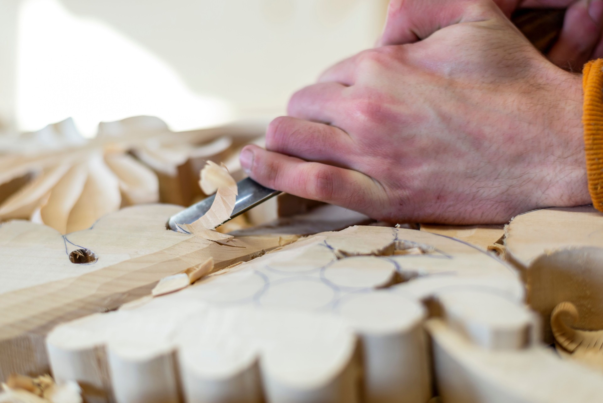 A woodcarver who works with a chisel on wood and makes wood carvings.